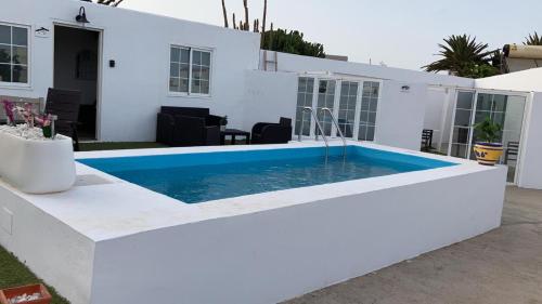 una piscina di fronte a una casa bianca di APARTAMETOS ELENA 11 a Lajares
