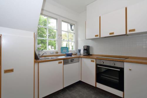 una cocina con armarios blancos y fregadero en Haus-Suedstrand-Appartement-12, en Westerland