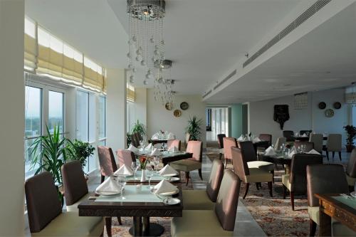 a dining room with tables and chairs and windows at Dushanbe Serena Hotel in Dushanbe