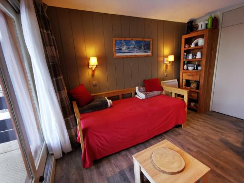 Schlafzimmer mit einem roten Bett und einem Tisch in der Unterkunft Meribel Le Creux de l'Ours in Les Allues