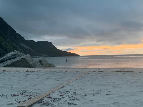 a sandy beach with a person in the water at Bayview Country House B&B - F94 VK64 in Ardara