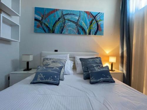 a bedroom with a white bed with blue pillows at Damari Luxury Retreat Villas Skiathos in Skiathos Town