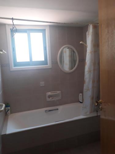 ein Bad mit einer Badewanne und einem Fenster in der Unterkunft SEAFRONT BEACH PARTY VILLA in Perivolia