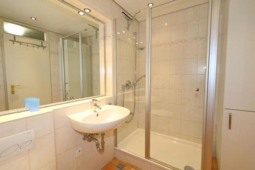 ein Bad mit einem Waschbecken und einer Glasdusche in der Unterkunft Haus am Meer App. 71 in Westerland