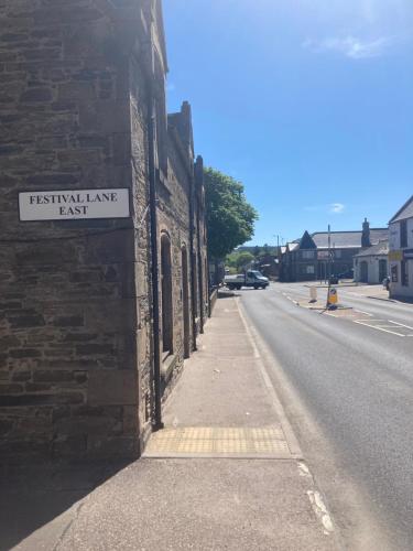 a brick building with a sign on the side of a street at The Annex Keith Self Catering WiFi Private Parking bkng in Keith