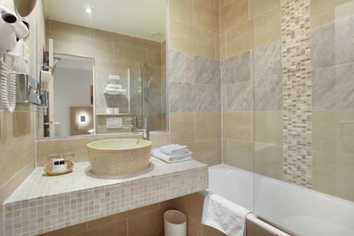 uma casa de banho com um lavatório, uma banheira e um espelho. em Hôtel LUX PICPUS em Paris