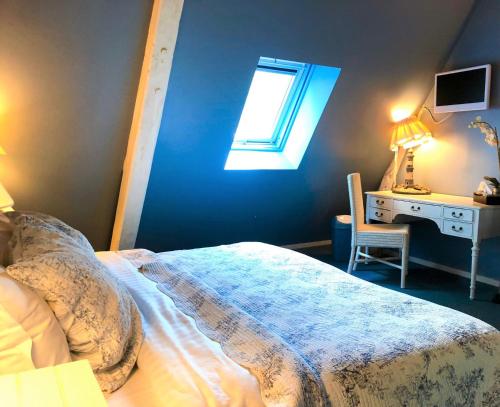 a bedroom with a bed and a desk and a window at Le Vieux Pressoir in Pont-lʼÉvêque