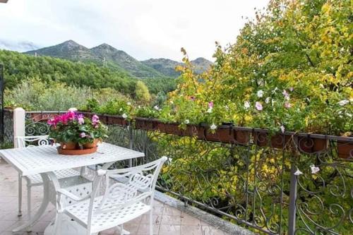 モラーノ・カーラブロにあるB&b Sant'Andreaの白いテーブルと椅子、花の咲くバルコニー