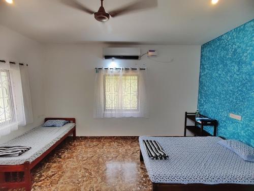 a room with two beds and a blue wall at Coco inn Goa in Candolim