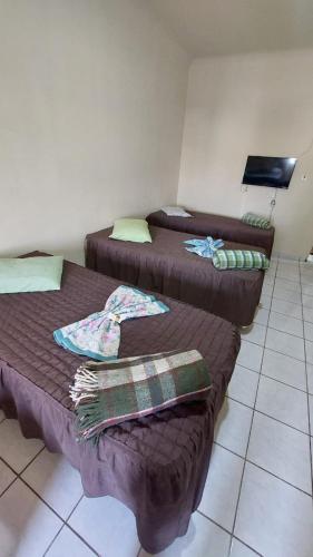 a room with two beds and a tiled floor at Hotel Casa Grande Max in Marília
