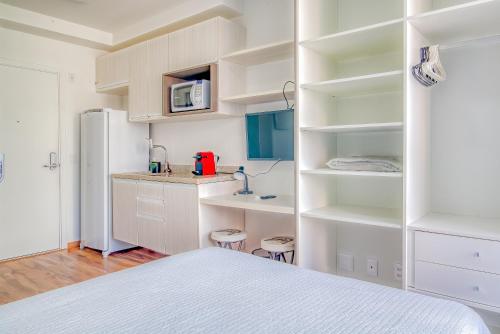 a white kitchen with white cabinets and a refrigerator at 360 Suítes Sé in Sao Paulo