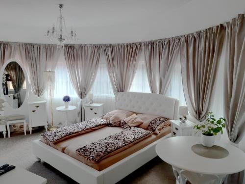 a white bedroom with a bed and a table at Penzion a Restaurace Belveder in Jáchymov