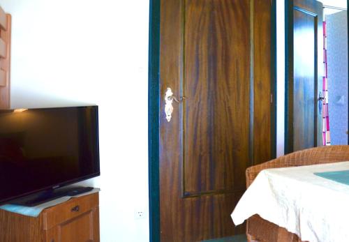 a living room with a television and a wooden door at Gästehaus Christophorus in Innerkrems
