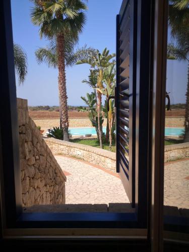 a view from a door of a resort with palm trees at Borgo Marino Plemmirio in Siracusa