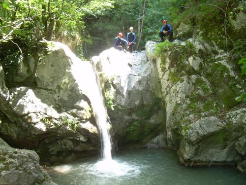 three people sitting on rocks near a waterfall at Il Belvedere in Civita