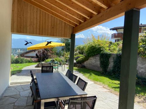 a patio with a table and a yellow umbrella at El Cantun - 7 Zimmer Einfamilienhaus mit 200m2 in Flims