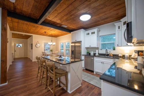 a kitchen with white cabinets and a island with bar stools at NEW-Ethel Rose Cottage-5 min to Magnolia Silos in Waco