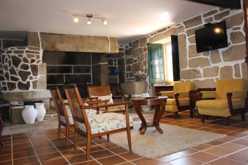 a living room with chairs and a stone wall at Alojamento Local Boega Hotel - Casas Boega I e II in Gondarém