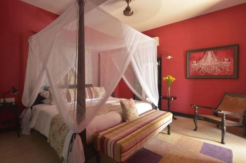 a bedroom with a canopy bed with a bench in it at Fort Tiracol Goa in Arambol