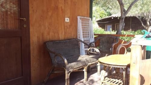 three wicker chairs and a table on a porch at Agriturismo Valle di Marco in Palinuro