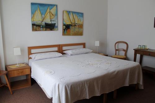 a bedroom with a bed with two tables and two paintings at Villa Corallo in Grado