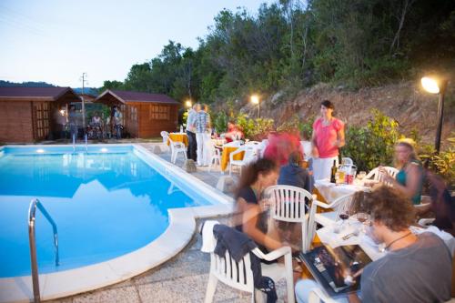 un groupe de personnes assises à côté d'une piscine dans l'établissement Residence Vacanza Mare, à Campo nell'Elba