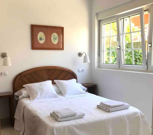 een slaapkamer met een wit bed en 2 handdoeken bij Apartamento céntrico en Finisterre in Fisterra