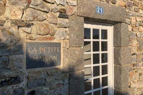 un edificio de piedra con una ventana y un cartel en él en SCIOTOT - Bord de mer - La petite maison, en Les Pieux