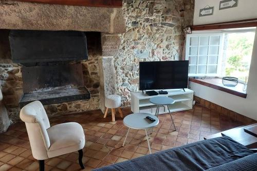 sala de estar con sofá, TV y chimenea en SCIOTOT - Bord de mer - La petite maison, en Les Pieux