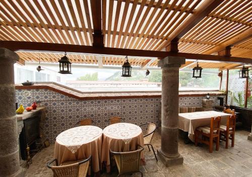 a patio with two tables and chairs under a wooden ceiling at Hotel Boutique Casa San Marcos in Quito