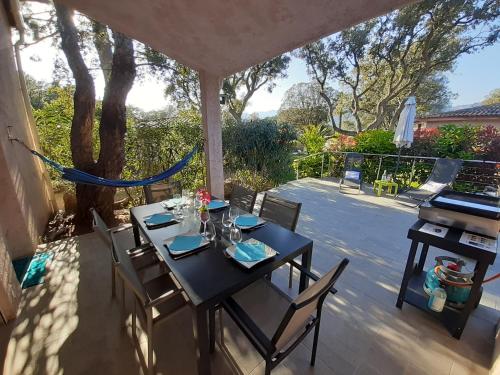 a black table and chairs on a patio with a hammock at Villa Pinarello climatisée avec piscine chauffée in Sainte-Lucie de Porto-Vecchio
