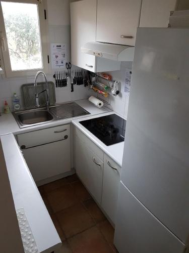 a white kitchen with a sink and a refrigerator at Villa Pinarello climatisée avec piscine chauffée in Sainte-Lucie de Porto-Vecchio