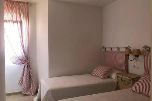 1 dormitorio con 2 camas y ventana en Apartamento primera línea de playa, en Finisterre