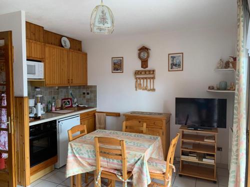 uma pequena cozinha com uma mesa e uma televisão em Studio Embrun plan d eau de 2 à 4 personnes situé 3 chemin de chadenas em Embrun