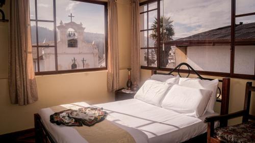a bedroom with a bed and a window with a church at Hotel La Cierva de San Marcos in Quito