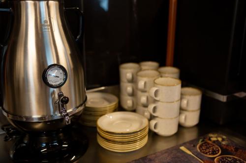 a coffee maker next to a pile of cups and plates at Hotel & SPA Hetman in Siedlce