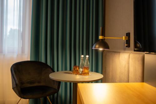 a table with a chair and two bottles on it at Hotel & SPA Hetman in Siedlce