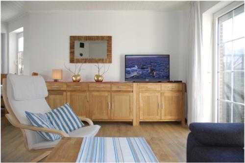 ein Wohnzimmer mit einem TV auf einem Holzschrank in der Unterkunft Haus Sandglöckchen in Greetsiel