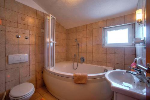 a bathroom with a tub and a toilet and a sink at Villa D&I in Vodice