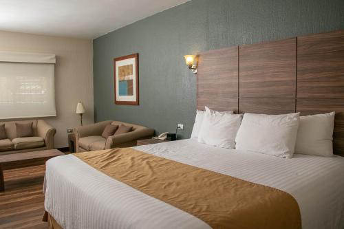 a hotel room with a large bed and a chair at Best Western Cumbres Inn Cd. Cuauhtemoc in Cuauhtémoc