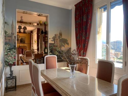 a dining room with a table and chairs and a window at Plein coeur de Monaco, à 300 mètres à pied du port de Monaco, 4 pièces dans des escaliers vue mer in Monte Carlo