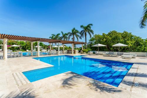 una piscina en un complejo con sillas y sombrillas en Gorgeous Magia Beachside Condos by Stella Rentals, en Playa del Carmen