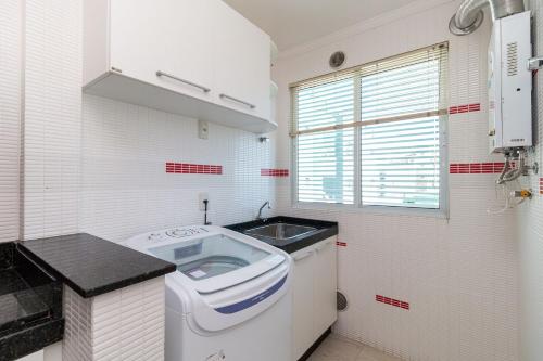 a small kitchen with a sink and a washing machine at Aluguel Apartamento 3 quartos vista mar Bombas SC in Bombinhas