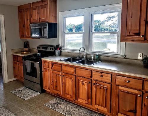 a kitchen with wooden cabinets and a sink and two windows at Beautiful, Modern & Convenient Home in Quinton, VA in Quinton