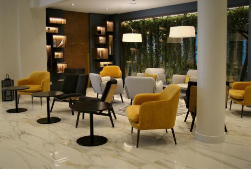 a waiting room with yellow chairs and tables at L'Amirauté Brest in Brest