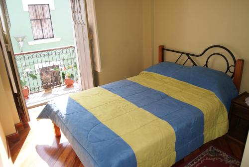 a bedroom with a bed with a blue and yellow blanket at Hotel La Cierva de San Marcos in Quito