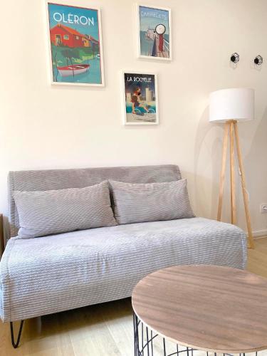 a living room with a couch and a table at Bleu Soleil Rochefort 3 étoiles in Rochefort