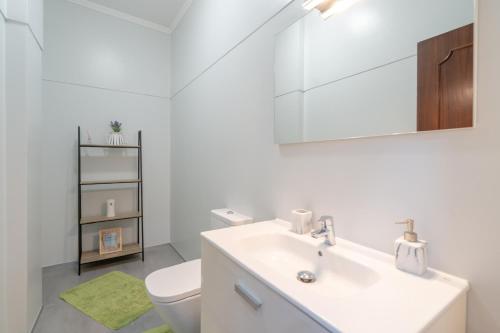 a white bathroom with a sink and a toilet at Flowers island house 3 in Caniço