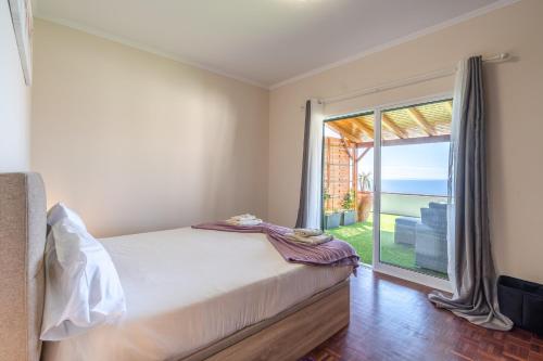 a bedroom with a bed and a large window at Flowers island house 3 in Caniço