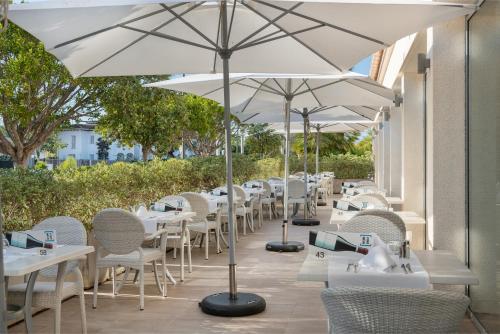 a row of tables with white umbrellas on a patio at Trendhotel Alcudia - Adults Only in Port d'Alcudia